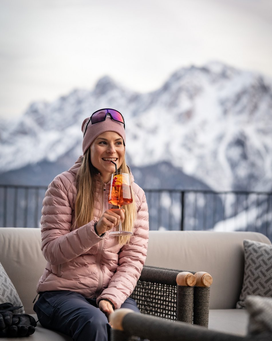 Il tuo hotel in Val Pusteria: Olangerhof Donna con giacca invernale rosa che beve un cocktail in montagna innevata