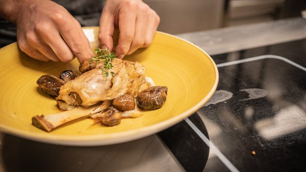 In Olang: a hotel with “Oh”, “Aah”, and “Wow” Chef garnishing meat dish with herbs on yellow plate