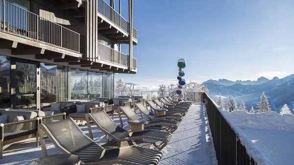 In Olang: a hotel with “Oh”, “Aah”, and “Wow” Sunny terrace with lounge chairs and sofas overlooking snowy mountains