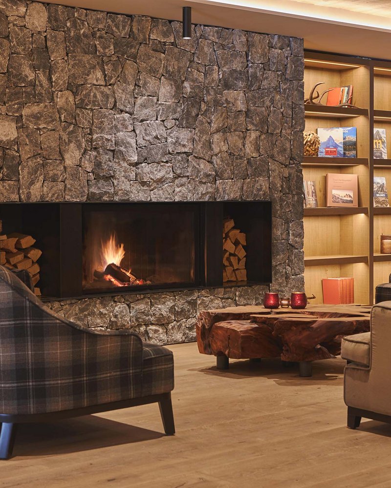 Il tuo hotel in Val Pusteria: Olangerhof Soggiorno accogliente con camino, divani e libreria in legno