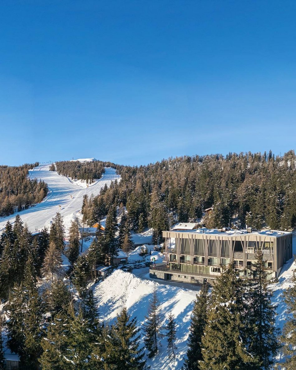 Il tuo hotel in Val Pusteria: Olangerhof Paesaggio invernale con piste da sci, alberi e edificio moderno sulle montagne