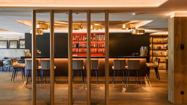 In Olang: a hotel with “Oh”, “Aah”, and “Wow” Modern bar with high stools and shelves of bottles lit by warm lighting