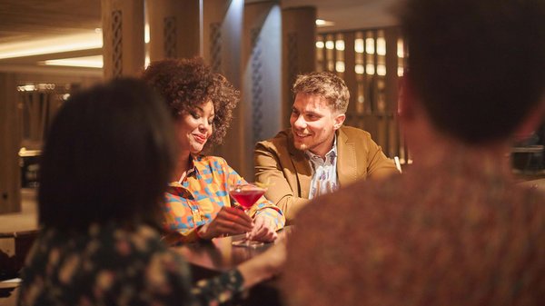 In Olang: a hotel with “Oh”, “Aah”, and “Wow” Two people chatting in a bar with cocktails on the table